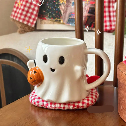 White ghost-shaped mug with black eyes and a small pumpkin on a red and white checkered coaster.